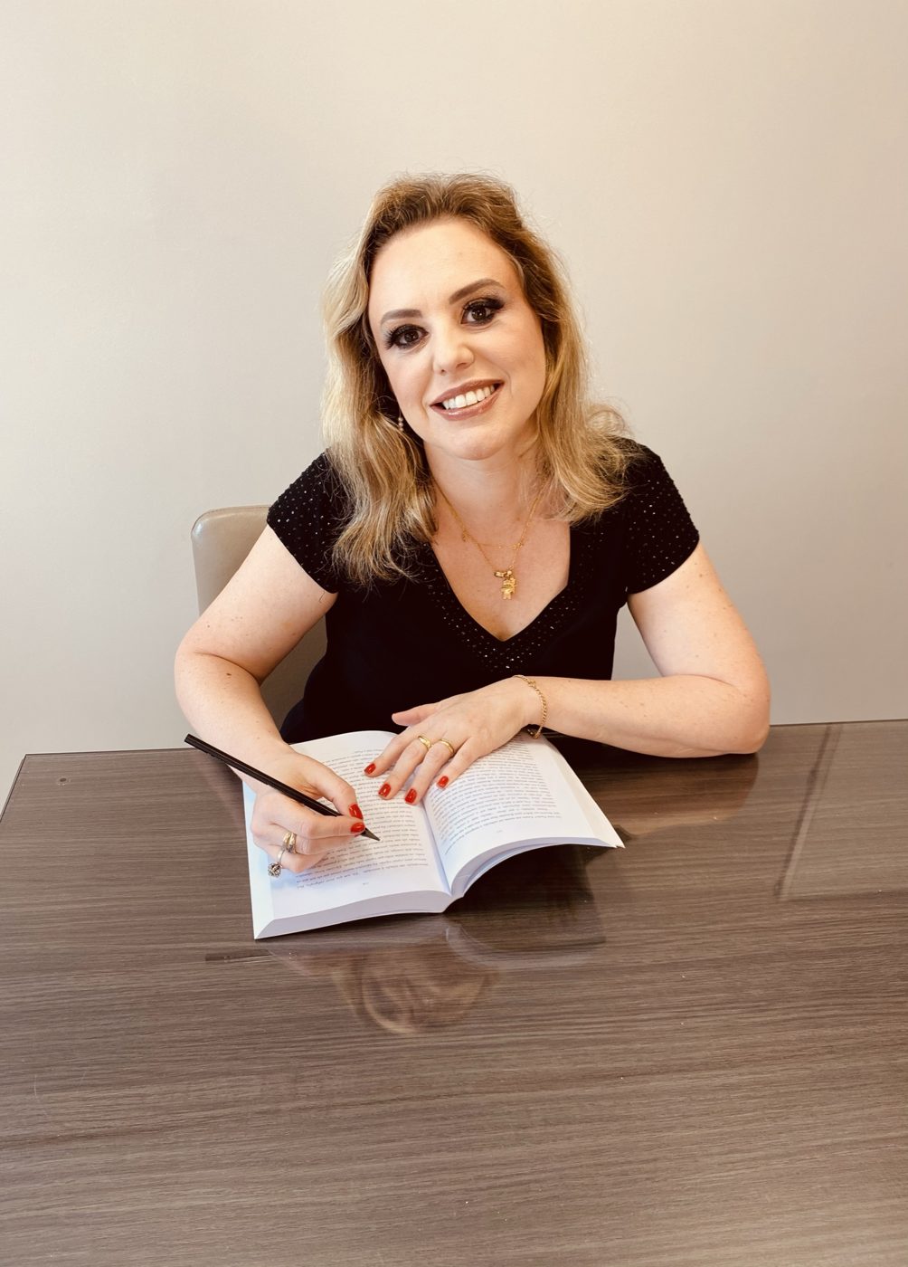 Dra. Vanessa Heck sorrindo à mesa do consultório